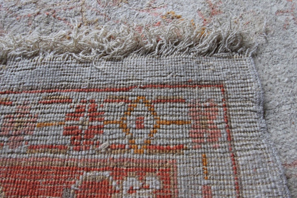 A late 19th-century hand-knotted Ushak wool carpet featuring soft terracotta borders surrounding a cream central field with muted botanical motifs. View III