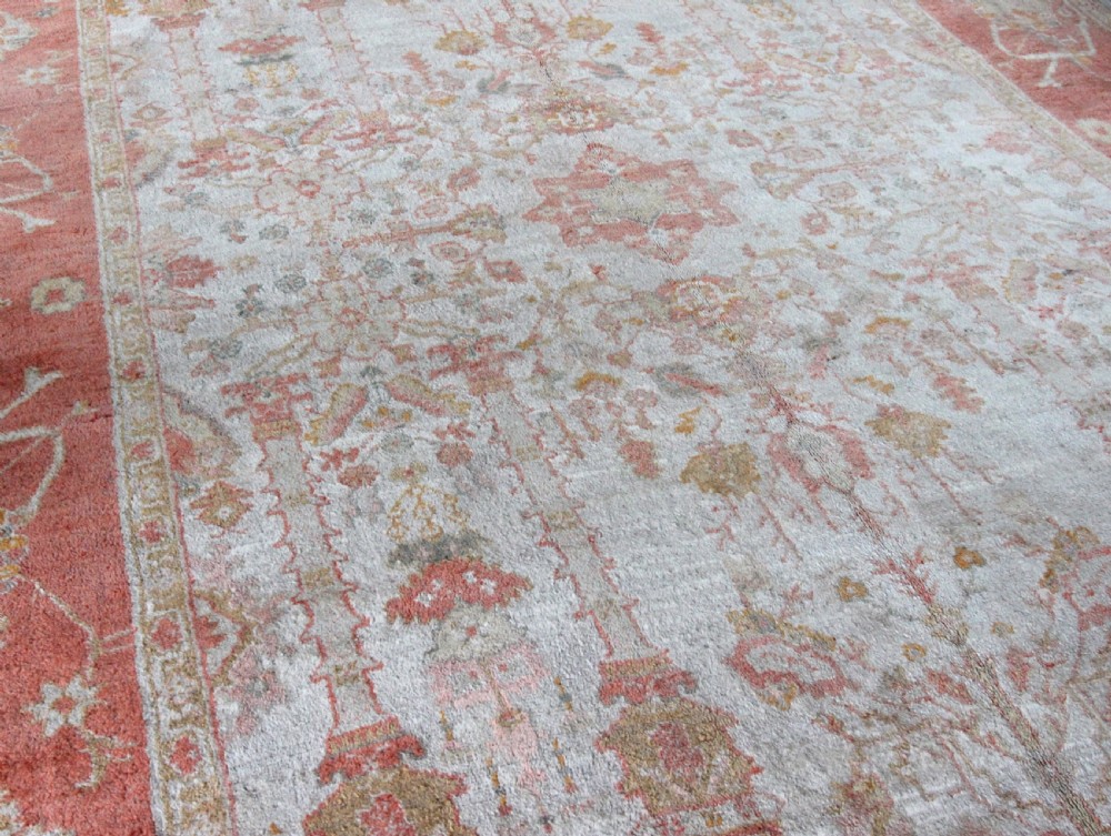 A late 19th-century hand-knotted Ushak wool carpet featuring soft terracotta borders surrounding a cream central field with muted botanical motifs. View IV