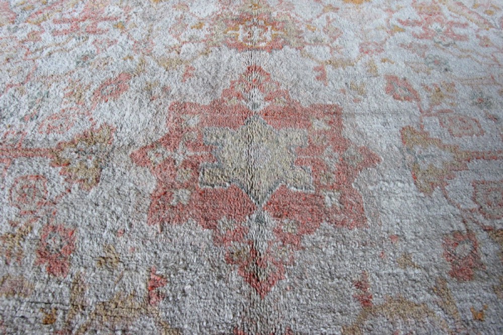 A late 19th-century hand-knotted Ushak wool carpet featuring soft terracotta borders surrounding a cream central field with muted botanical motifs. View V