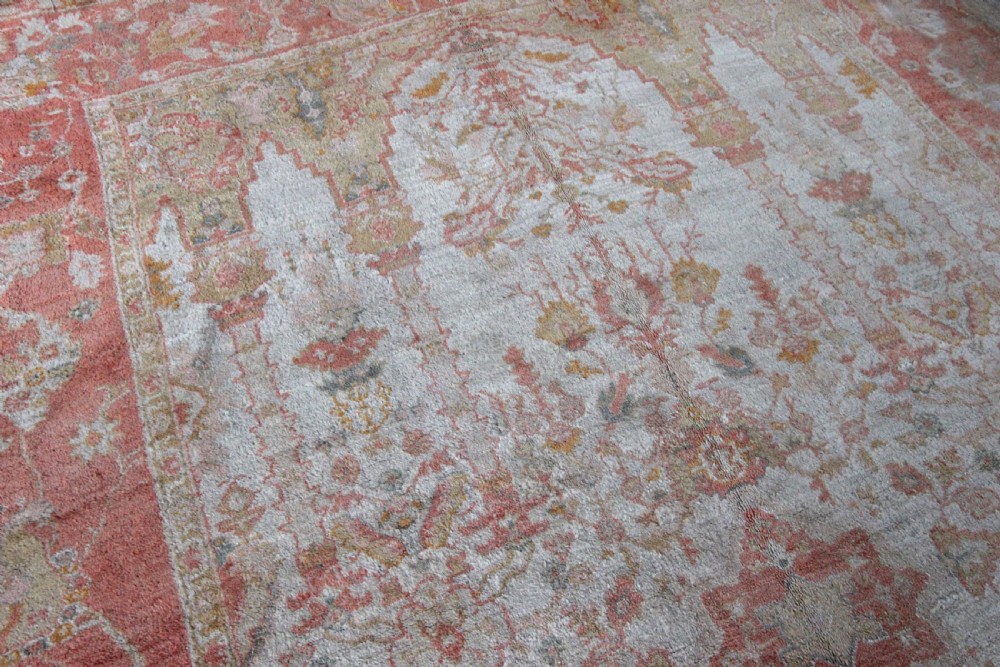 A late 19th-century hand-knotted Ushak wool carpet featuring soft terracotta borders surrounding a cream central field with muted botanical motifs. View VI
