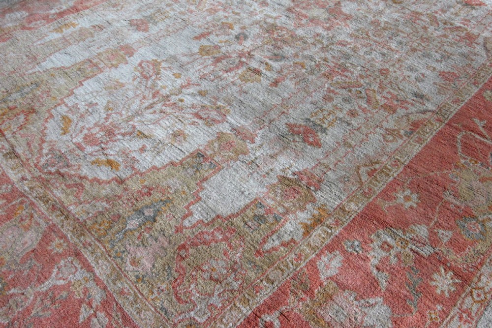 A late 19th-century hand-knotted Ushak wool carpet featuring soft terracotta borders surrounding a cream central field with muted botanical motifs. View VII