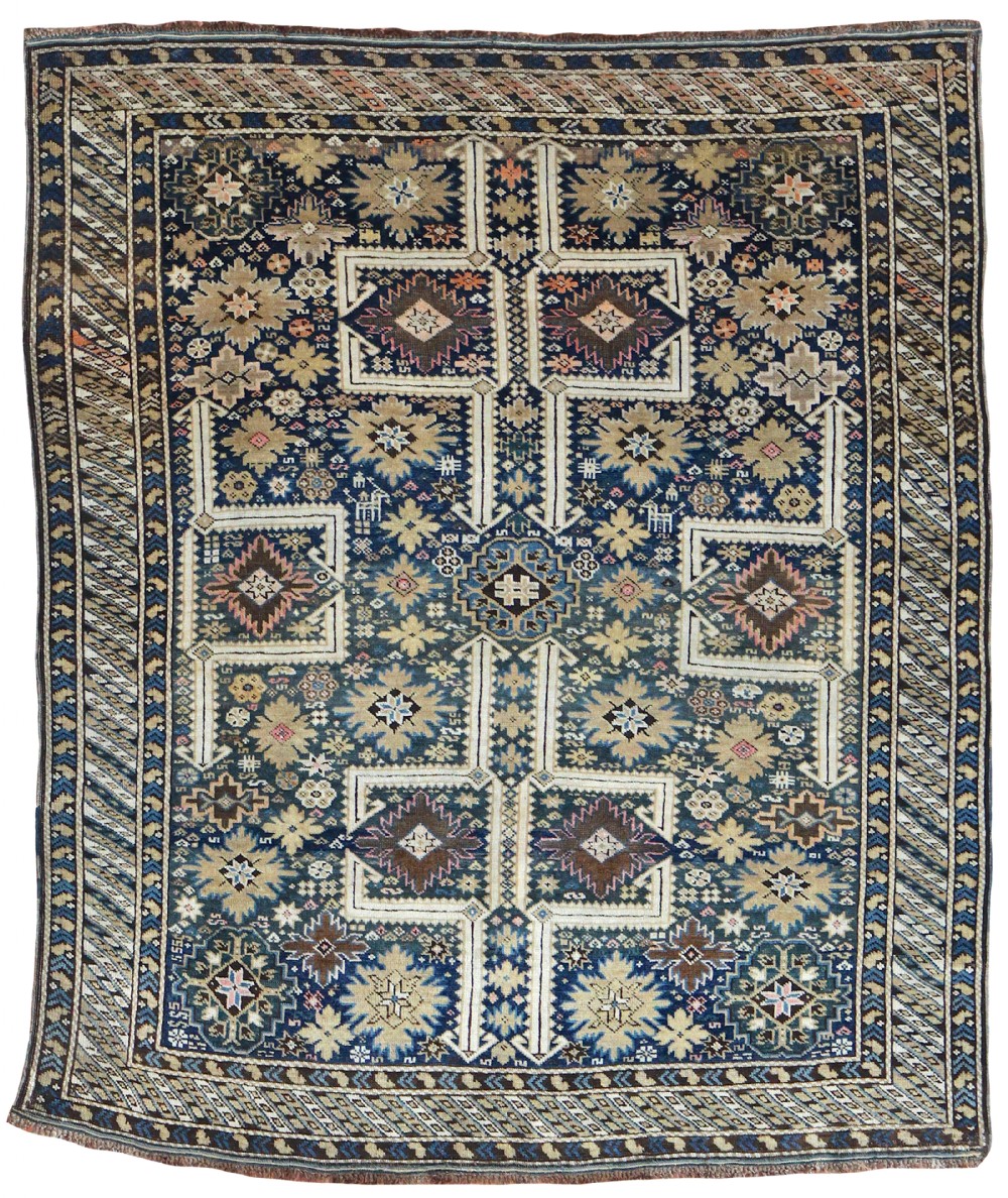 An antique hand-knotted Caucasian Kuba wool rug featuring geometric diamond medallions and star motifs in navy blue, ivory, and beige.