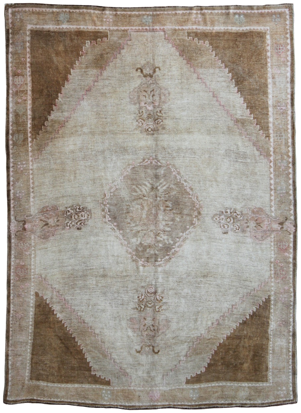 An antique Anatolian Ushak wool carpet featuring a central stepped diamond medallion in muted beige, light brown, and soft pink tones with a decorative border.