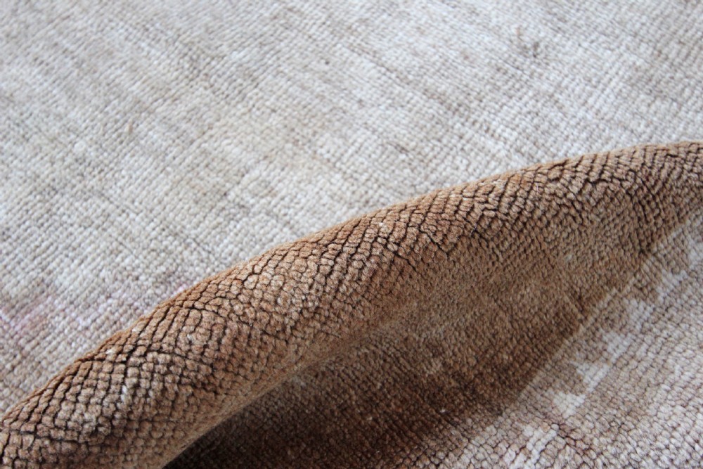 An antique Anatolian Ushak wool carpet featuring a central stepped diamond medallion in muted beige, light brown, and soft pink tones with a decorative border. View III