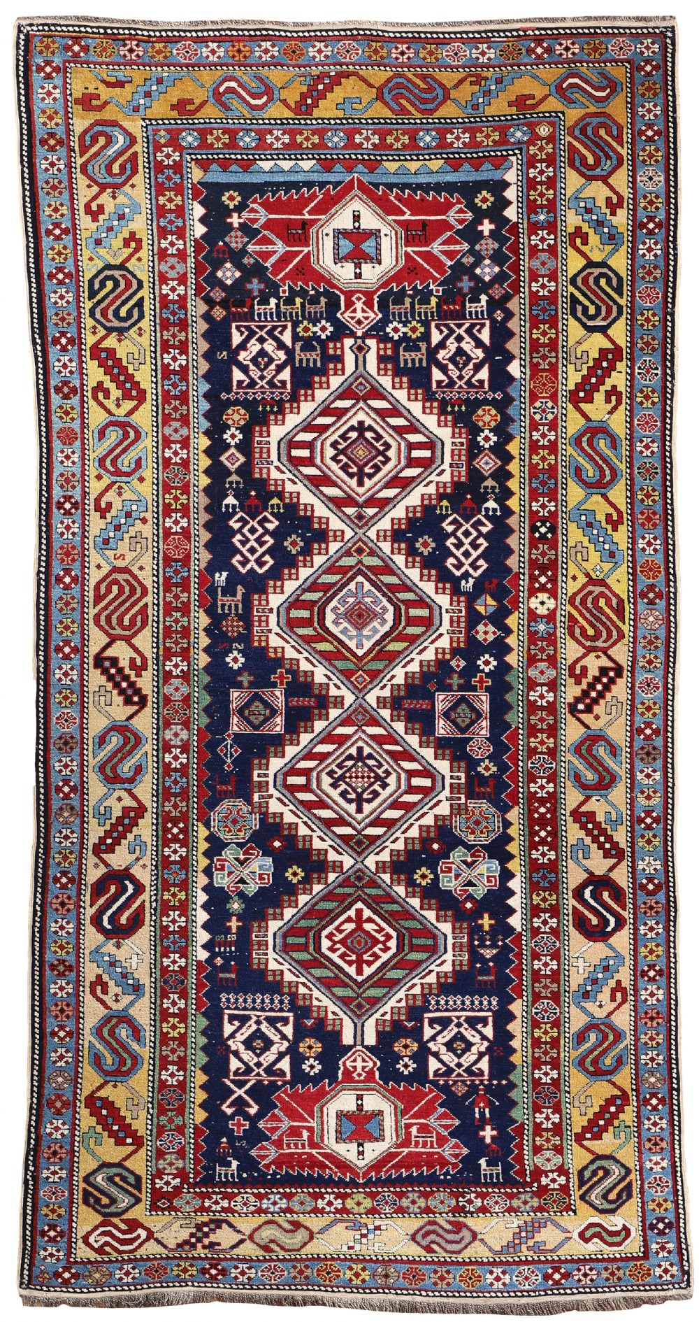 An antique Shirvan carpet featuring a navy blue field with stacked diamond medallions and geometric multi-coloured borders.