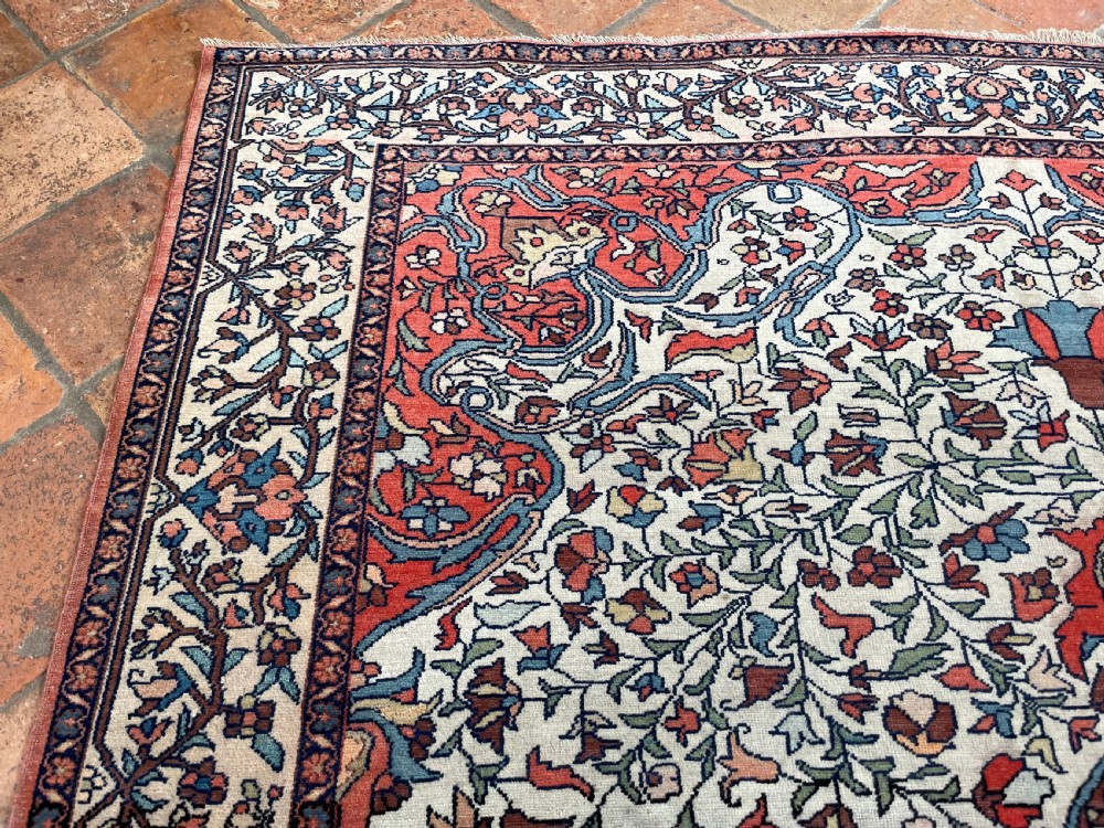 An antique Persian Malayer wool rug featuring a dark navy stepped central medallion surrounded by a floral ivory field, coral spandrels, and a patterned main border. View VI