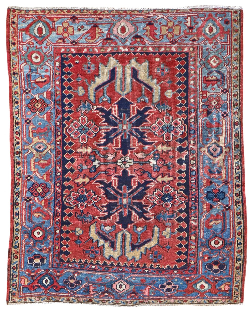 A hand-knotted Persian Karaja rug featuring a red geometric field with central star medallions framed by a light blue patterned border.