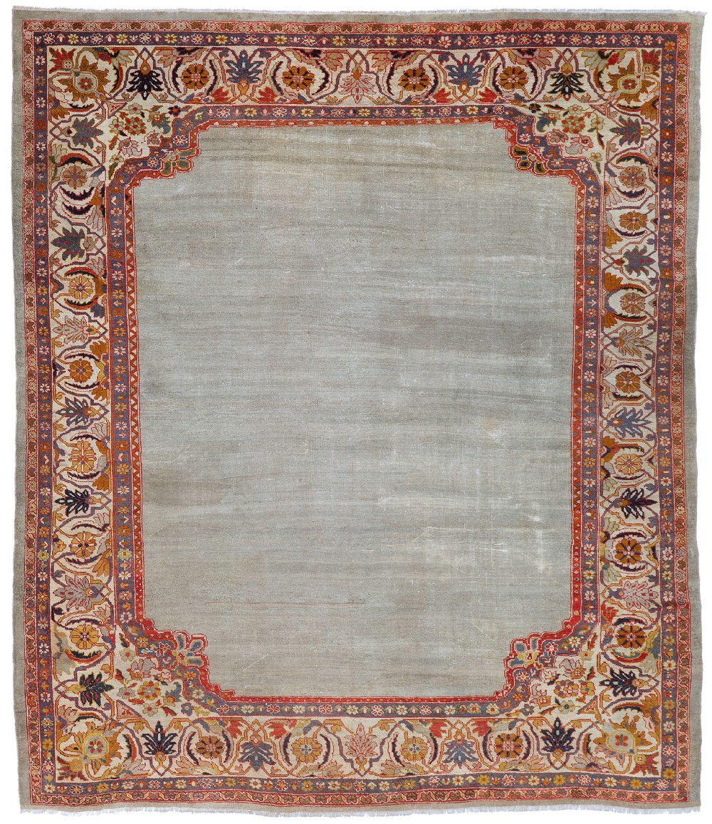 An antique Persian Ziegler wool carpet featuring a muted grey open field surrounded by an intricate floral palmette border in terracotta, cream, and navy tones.