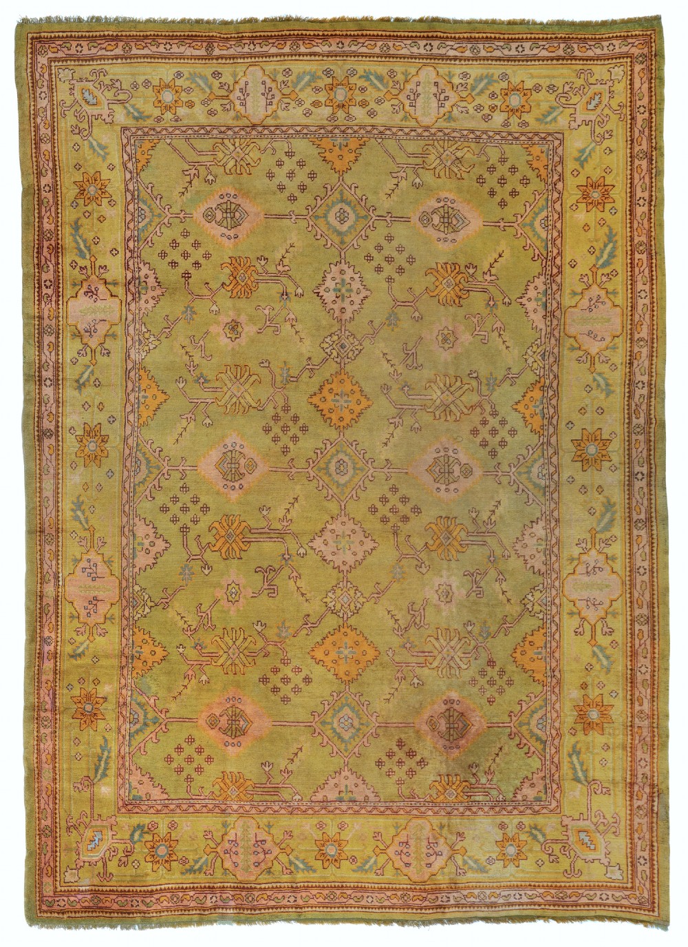An olive green hand-knotted wool carpet decorated with geometric medallions, floral motifs, and a patterned border in yellow, peach, and muted blue tones.
