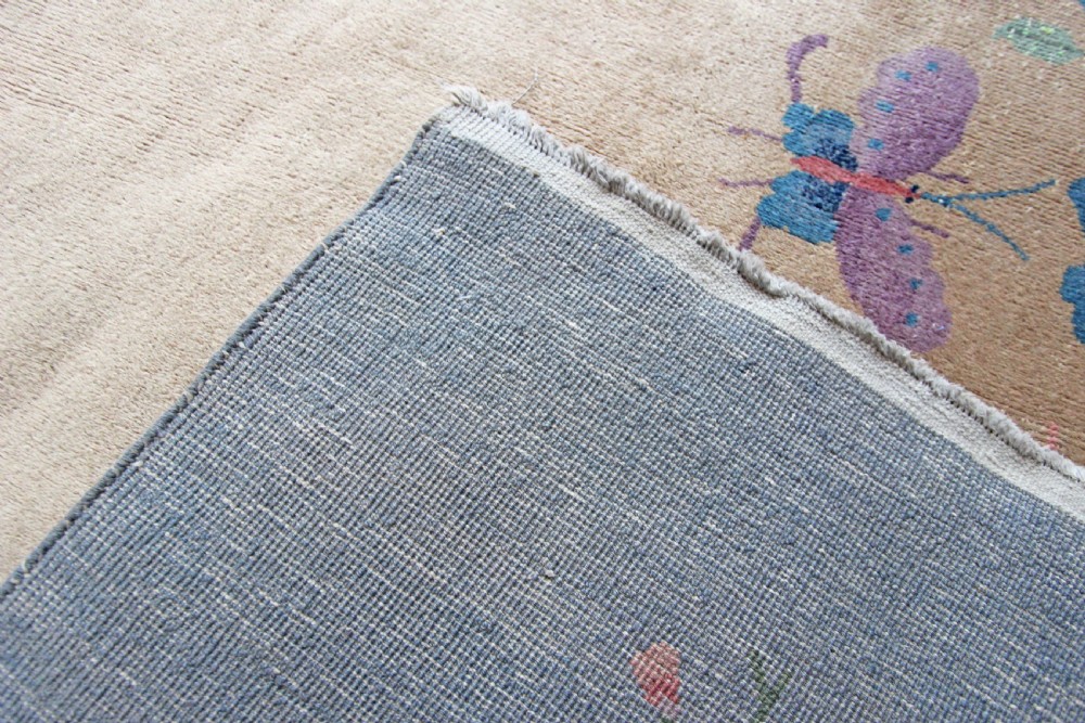 A rectangular Chinese Art Deco wool carpet featuring a beige central field bordered in periwinkle blue with asymmetrical floral and bird motifs. View III
