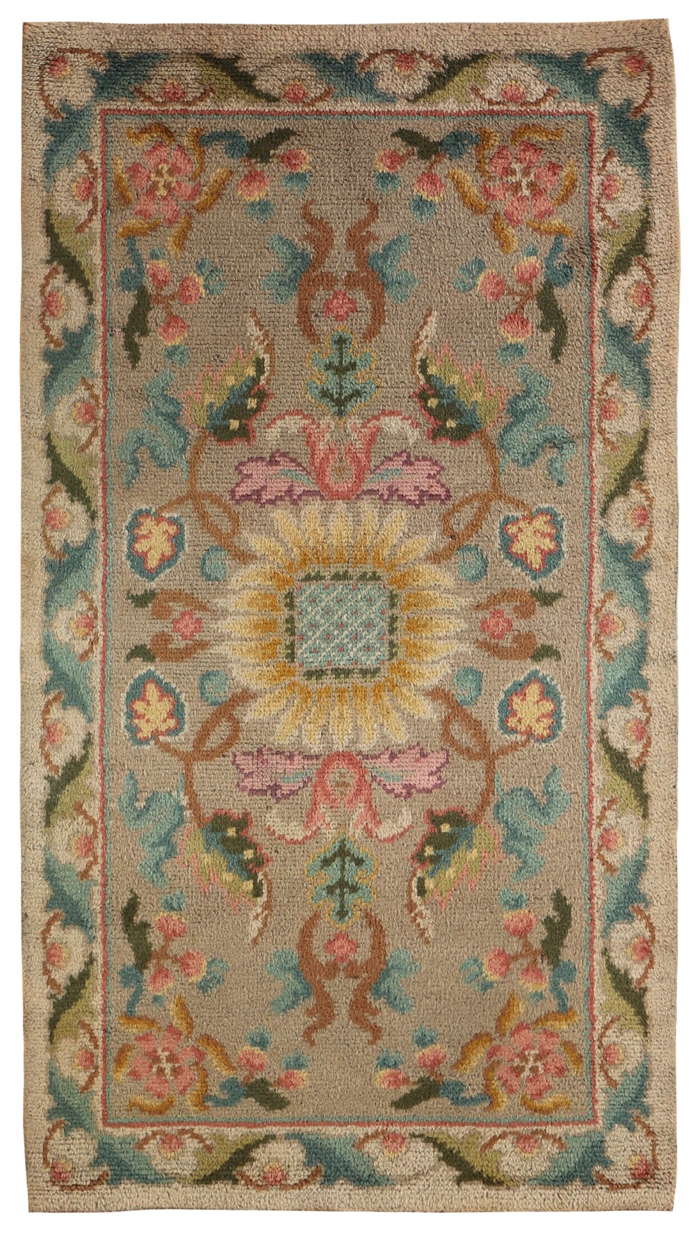 An antique hand-knotted wool Donegal rug featuring a central stylised floral motif surrounded by a scrolling leaf border in shades of teal, pink, and yellow on a neutral beige background.