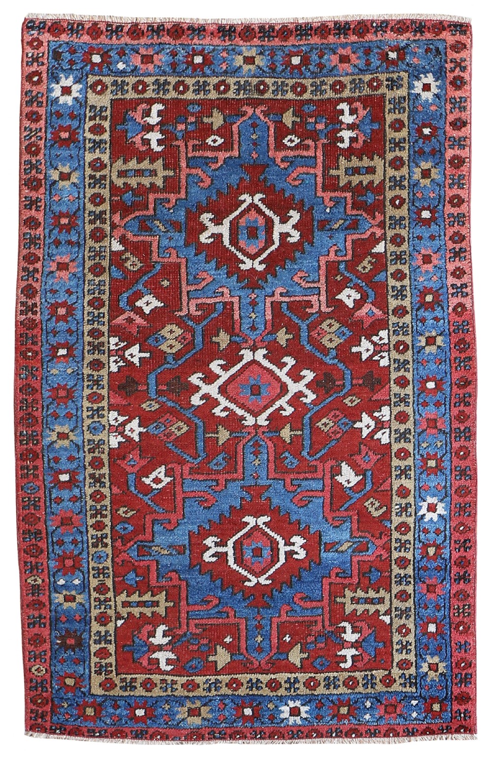 An antique hand-knotted Persian Heriz rug featuring a bold geometric red and blue medallion design framed by a multi-tiered border.