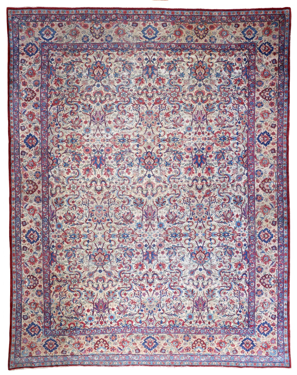 An antique hand-knotted Kirman carpet featuring an intricate floral pattern in shades of red, blue, and pink on a cream ground with a decorative multi-banded border.
