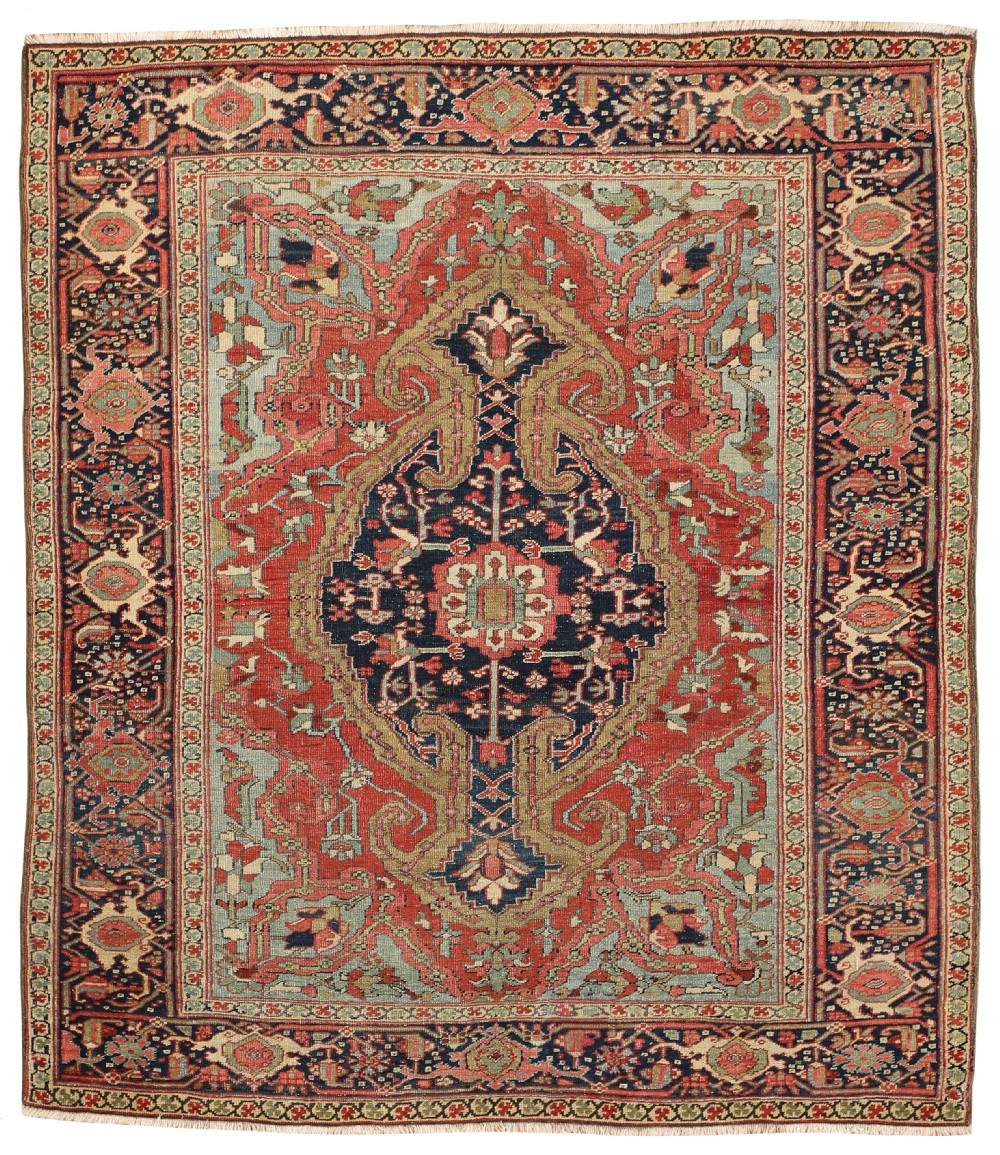 An antique hand-knotted Persian Heriz wool carpet featuring a large central geometric medallion in navy blue and terracotta with multi-tiered patterned borders.