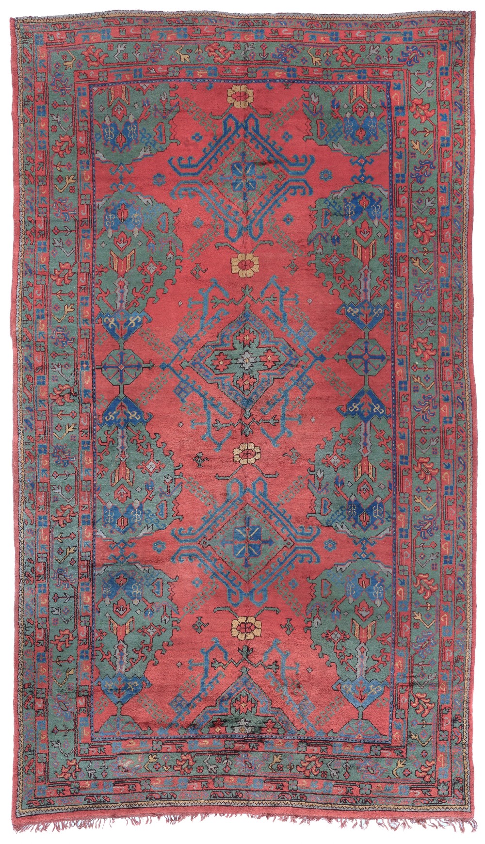 An antique hand-knotted Ushak wool carpet featuring a terracotta red field with central diamond medallions framed by sage green and blue geometric floral borders.