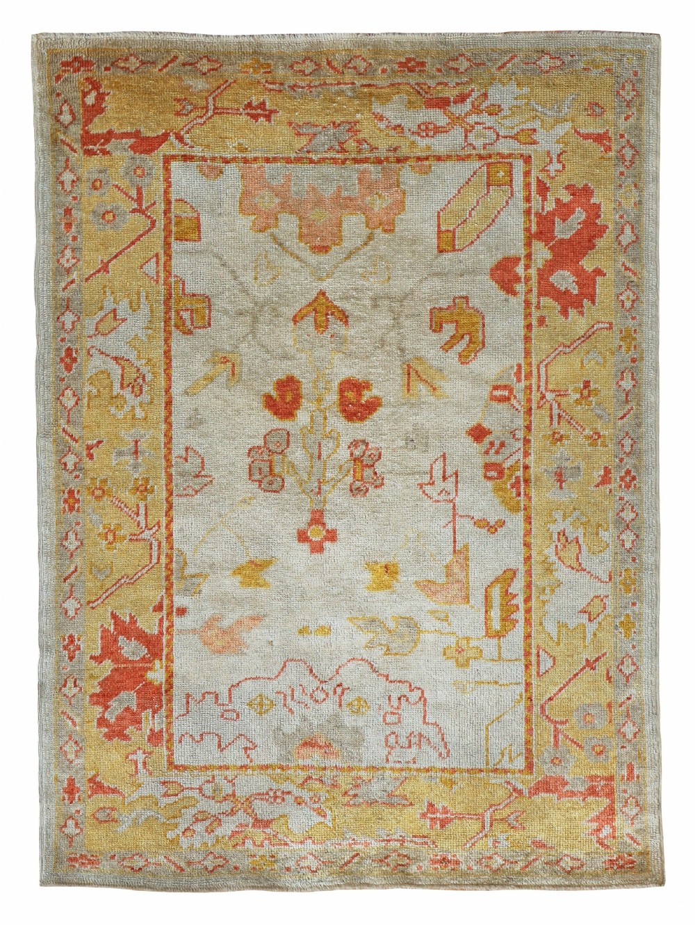 An antique Ushak wool rug featuring a cream central field with muted orange and yellow floral motifs framed by a wide ochre patterned border.