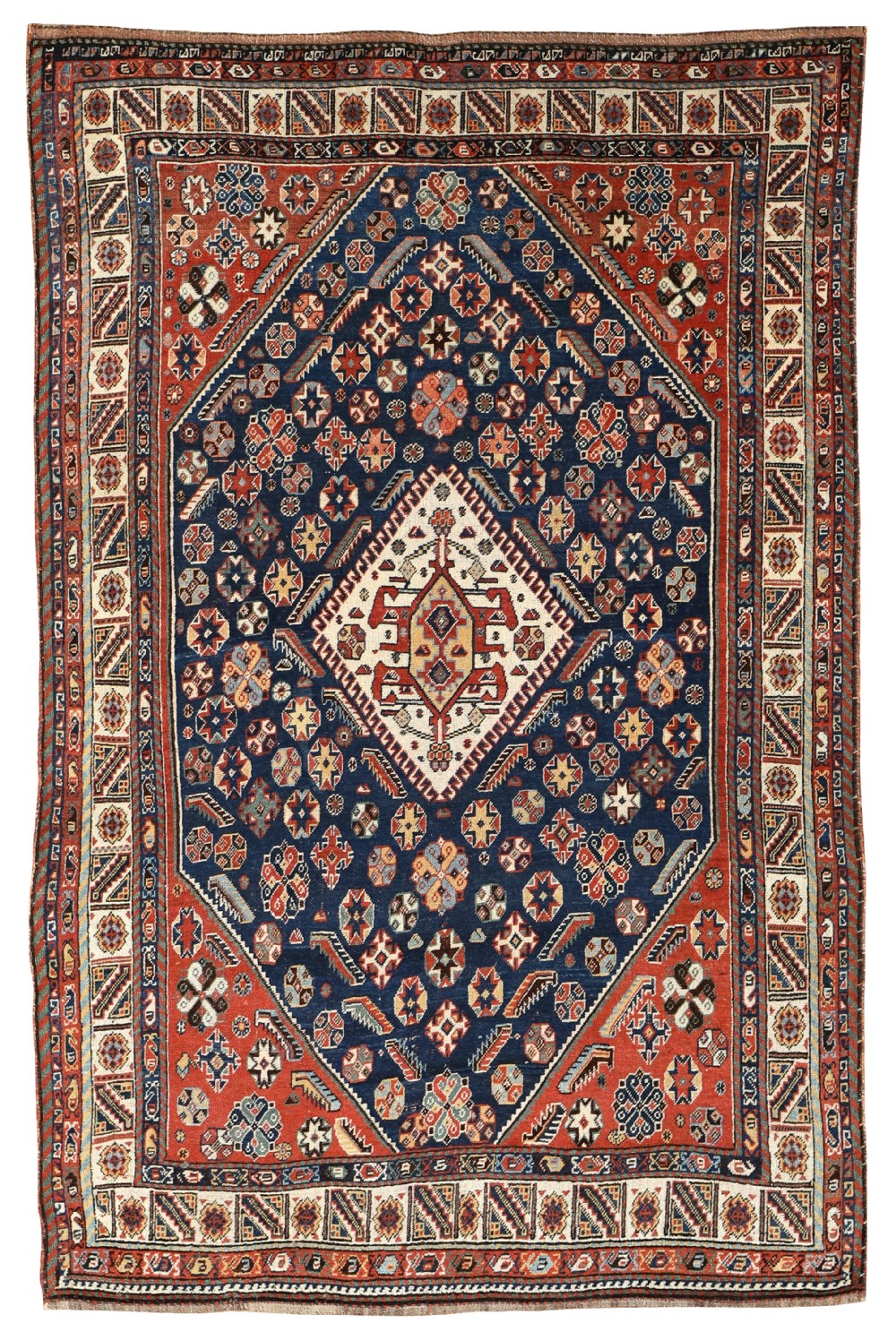 An antique hand-knotted Qashqai wool rug featuring a central diamond medallion surrounded by dense geometric motifs in navy blue, terracotta red, and ivory tones.