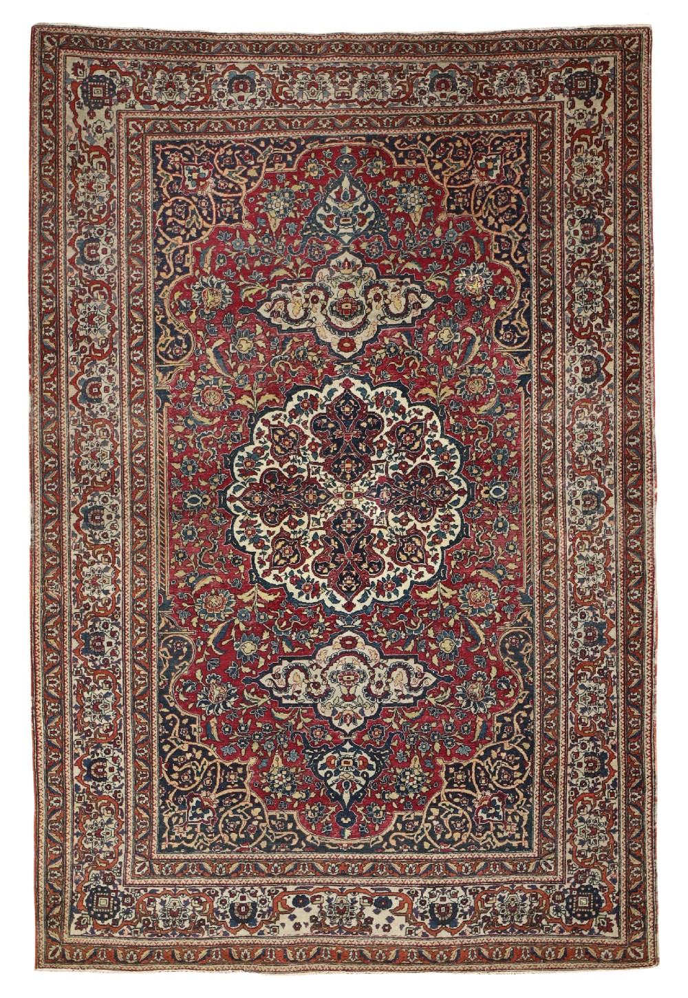A hand-knotted antique Isfahan carpet featuring a central medallion pattern on a crimson red field with navy blue floral borders.