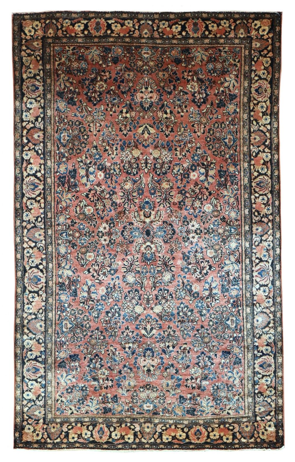 A rectangular hand-knotted antique Sarouk rug featuring intricate floral sprays in blue and cream across a terracotta red field with a dark blue multi-banded border.