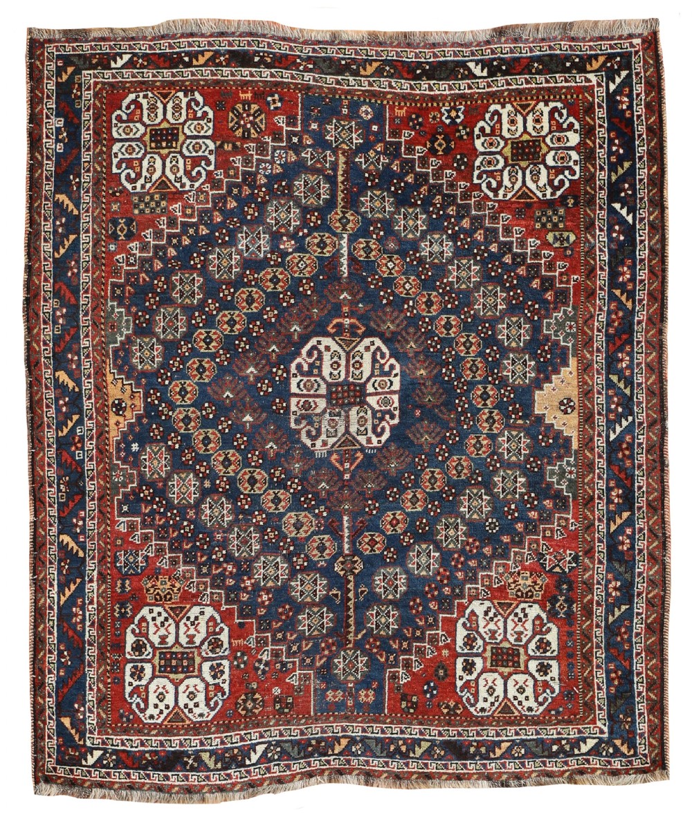An antique hand-knotted Shiraz wool rug featuring a dark navy central field with geometric diamond motifs, red corner spandrels, and multi-tiered borders.