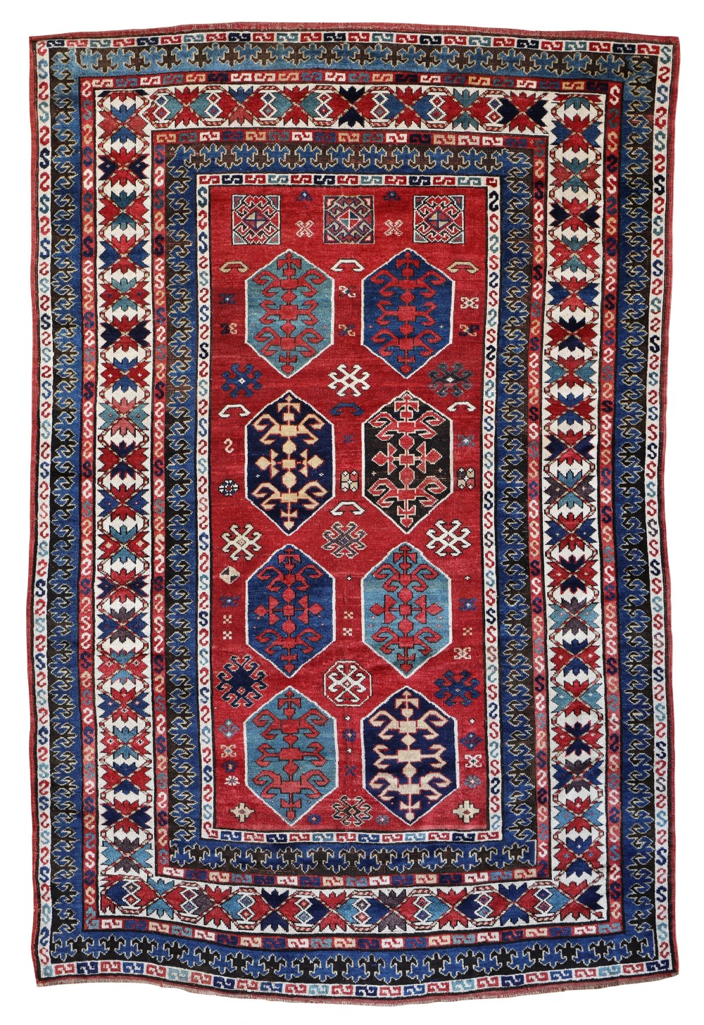An antique rectangular hand-knotted wool Kazak rug featuring a red field with geometric hexagonal medallions and multi-coloured borders.