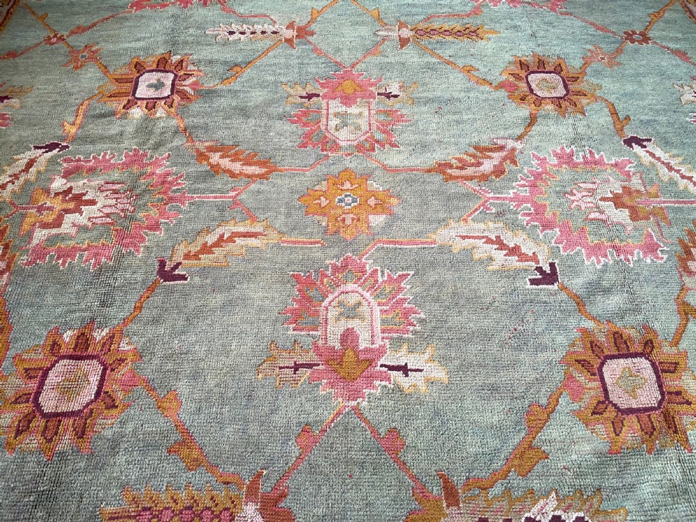 An antique hand-knotted wool Ushak carpet featuring a muted teal field with a lattice of floral palmettes surrounded by a wide terracotta border. View V