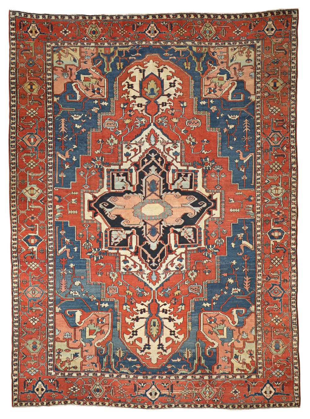 An antique hand-knotted Serapi carpet featuring a large geometric central medallion in terracotta red, navy blue, and ivory framed by decorative borders.