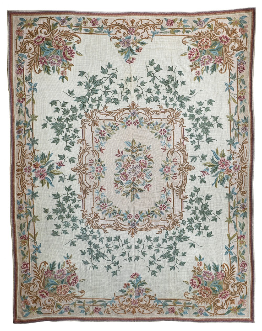 A rectangular Portuguese needlepoint rug featuring a central floral medallion surrounded by trailing ivy vines, pastel floral sprays, and a scrollwork border on a cream background.