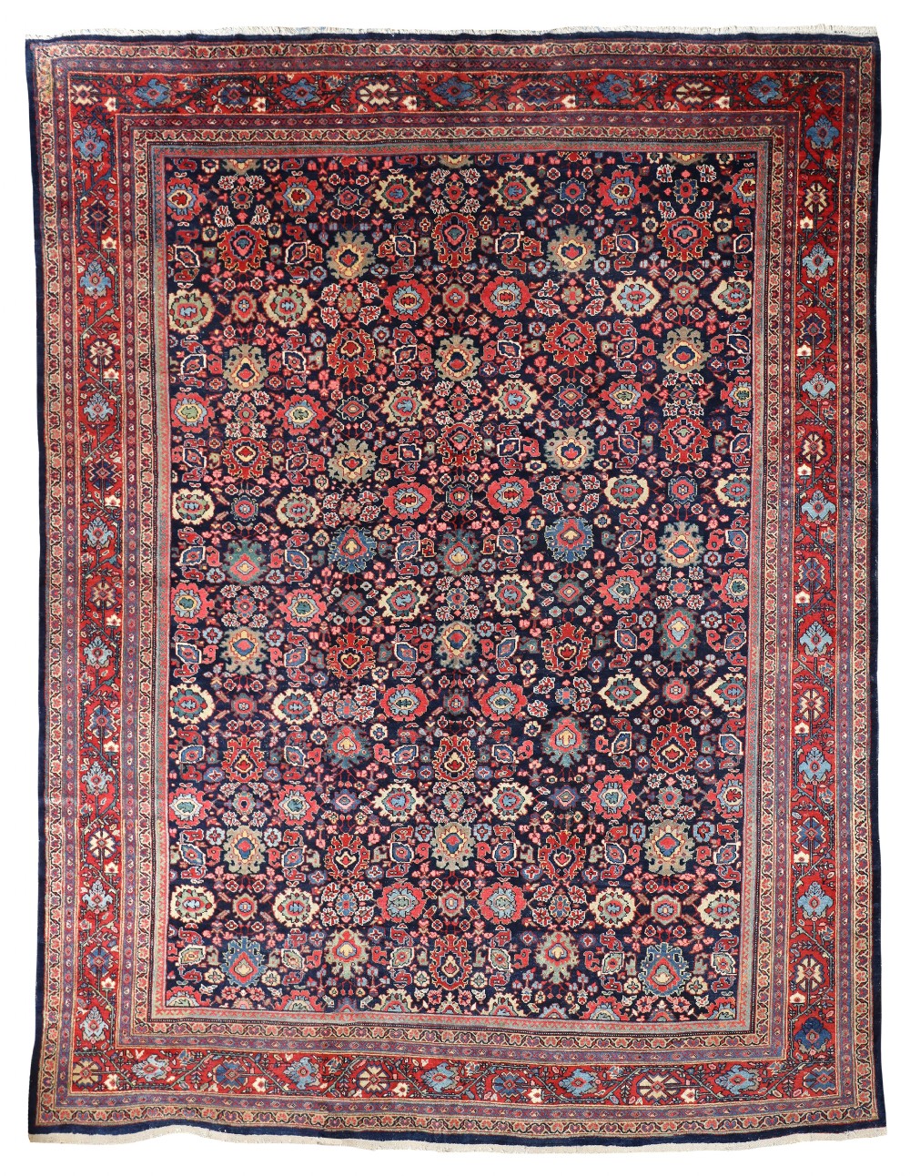 An antique hand-knotted Persian Mahal carpet featuring a dense dark blue field patterned with colourful floral palmettes framed by wide red borders.