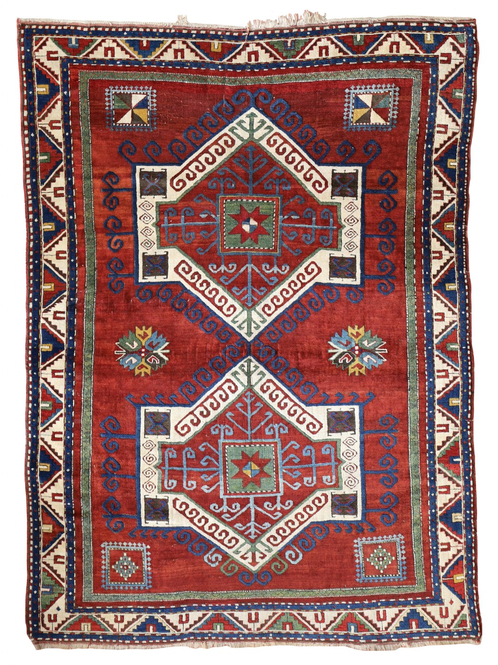 An antique Kazak wool rug featuring two large central geometric medallions on a deep red field with multi-coloured geometric borders.