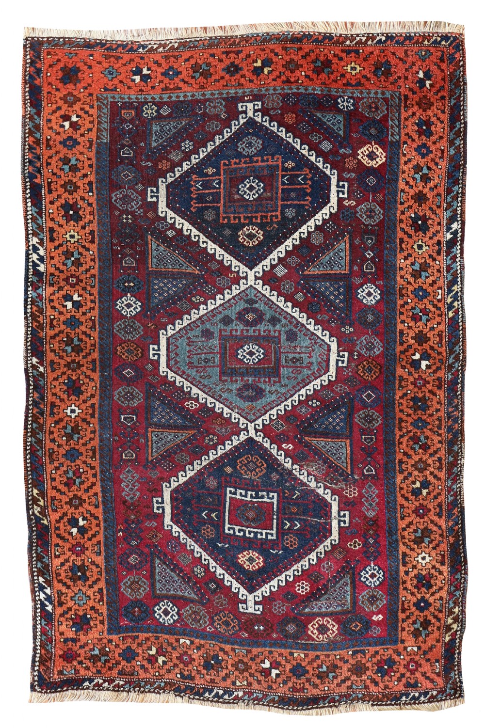A rectangular hand-woven antique Yuruk rug featuring three central geometric diamond medallions in navy and blue against a red field with patterned orange borders.