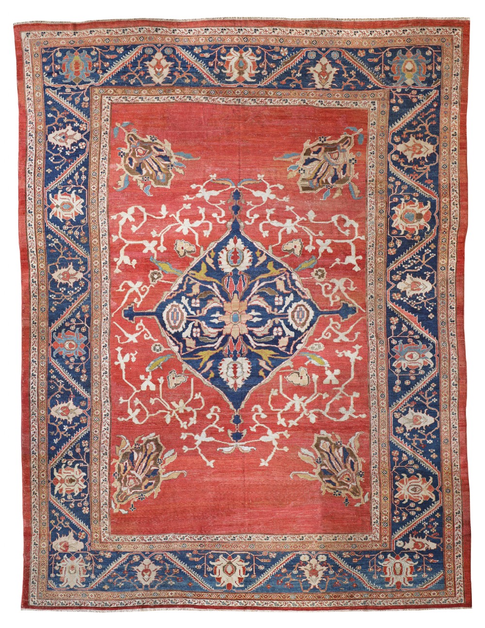 A rectangular hand-knotted wool carpet featuring a terracotta red field with a navy blue central medallion, floral spandrels, and a decorative blue border.