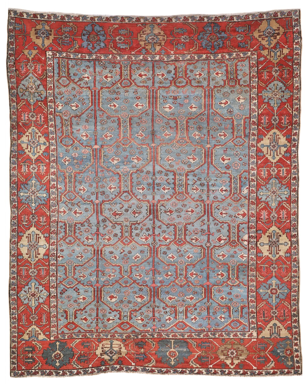 An antique Bakshaish Persian wool carpet featuring a light blue field with repeating geometric motifs surrounded by a wide terracotta red border.