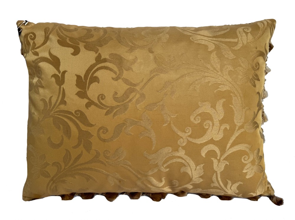 A rectangular beige tapestry cushion featuring pink floral scrollwork and tasselled edge trim. View V