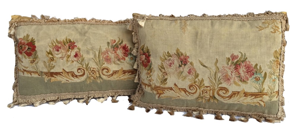 A rectangular beige tapestry cushion featuring pink floral scrollwork and tasselled edge trim. View VI