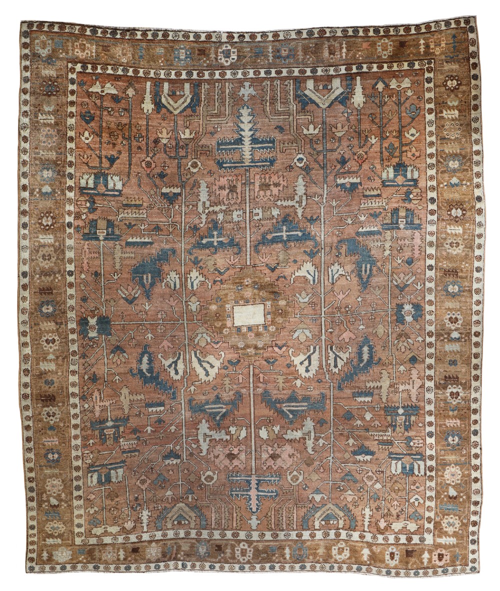 An antique Bakshaish wool carpet featuring stylized tree and geometric floral motifs in terracotta, brown, blue, and cream tones.