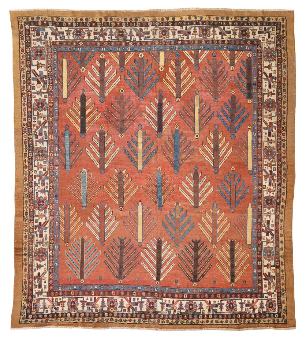 An antique Persian Bakshaish wool carpet featuring repeating stylised tree motifs across a terracotta red field surrounded by multi-band geometric borders.
