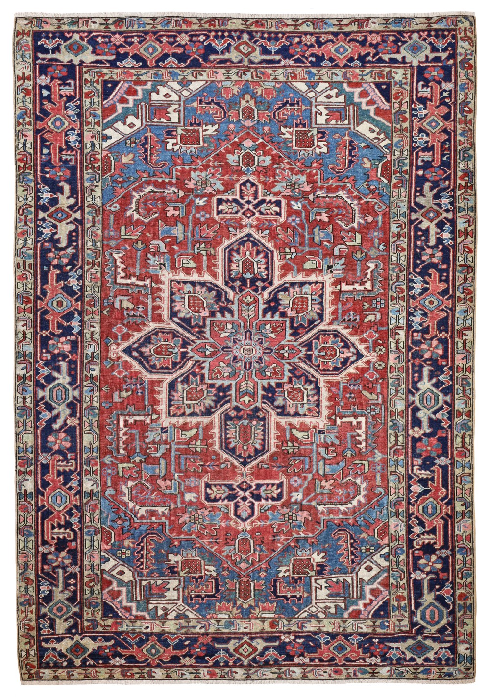 A hand-knotted antique Heriz carpet featuring a large geometric central medallion in indigo and red, framed by angular spandrels and a multi-tiered patterned border.