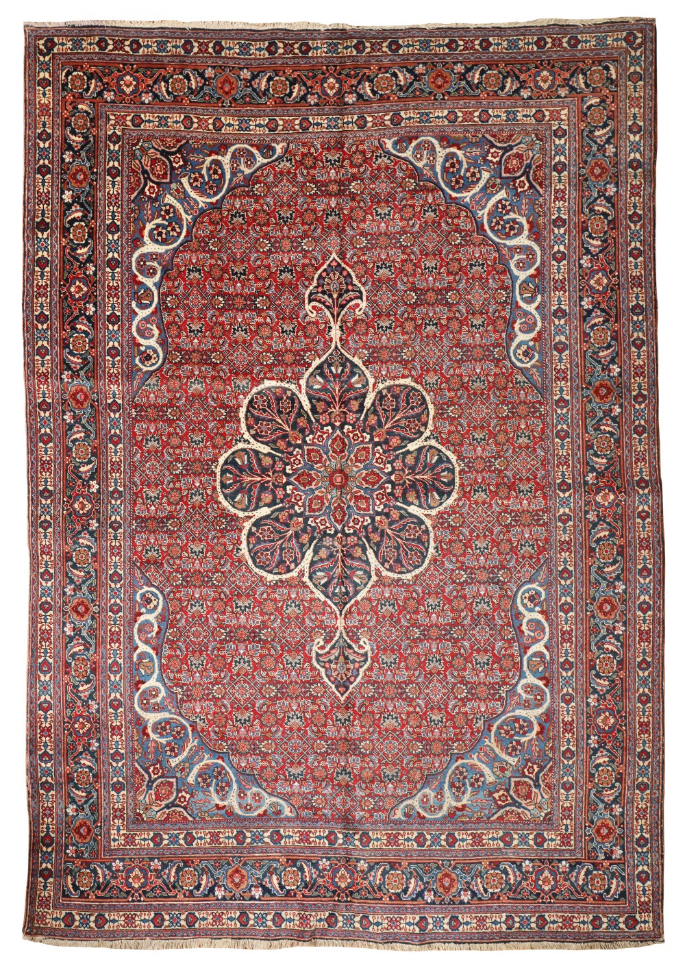 An antique hand-knotted Persian Tabriz carpet featuring a central lobed floral medallion on a crimson red field surrounded by intricate navy blue floral borders.