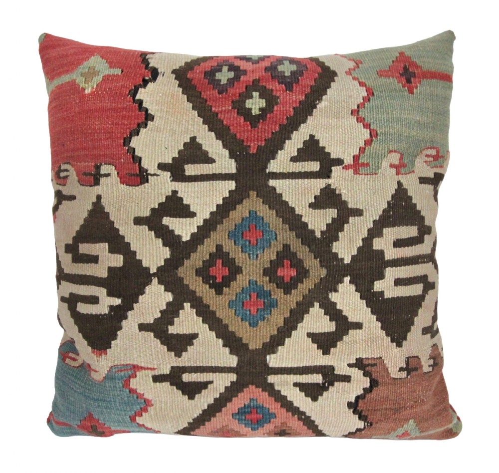 A square antique kilim cushion woven with geometric diamond patterns in cream, dark brown, red, terracotta, and soft blue tones.