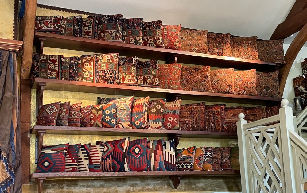 A square antique kilim cushion woven with geometric diamond patterns in cream, dark brown, red, terracotta, and soft blue tones. View VII