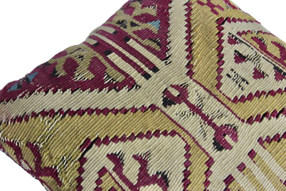 A square cushion made from handwoven kilim textile featuring geometric diamond motifs in ochre yellow, burgundy red, and beige. View VIII