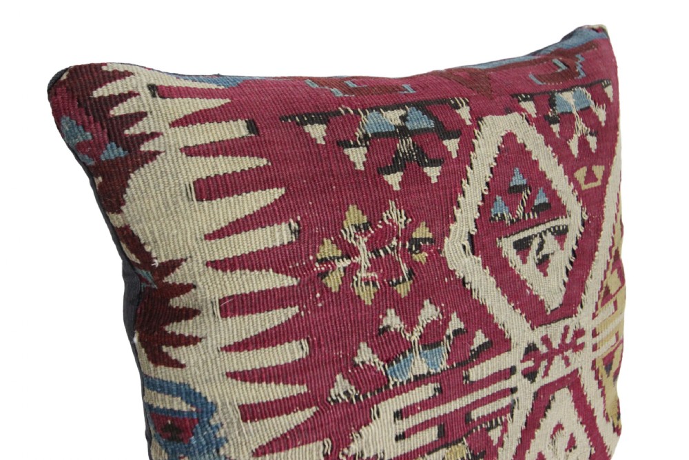 A square scatter cushion crafted from a hand-woven kilim textile in deep crimson red, cream, and soft blue geometric patterns. View VII