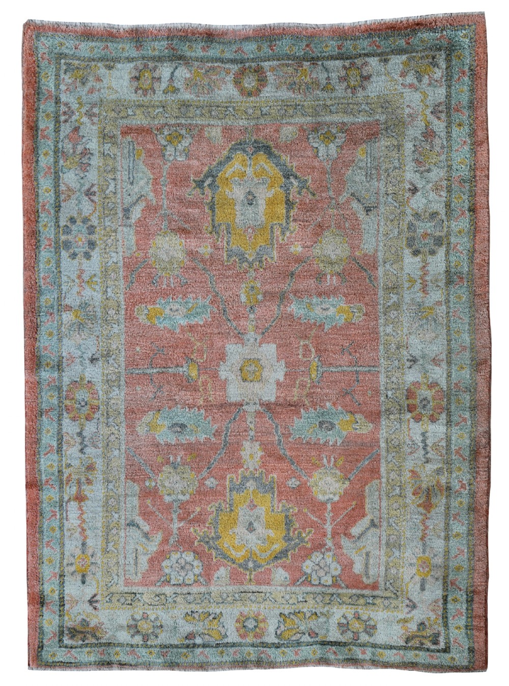 An antique wool Ushak carpet featuring a terracotta central field decorated with pale blue and mustard yellow floral medallions inside a wide patterned border.