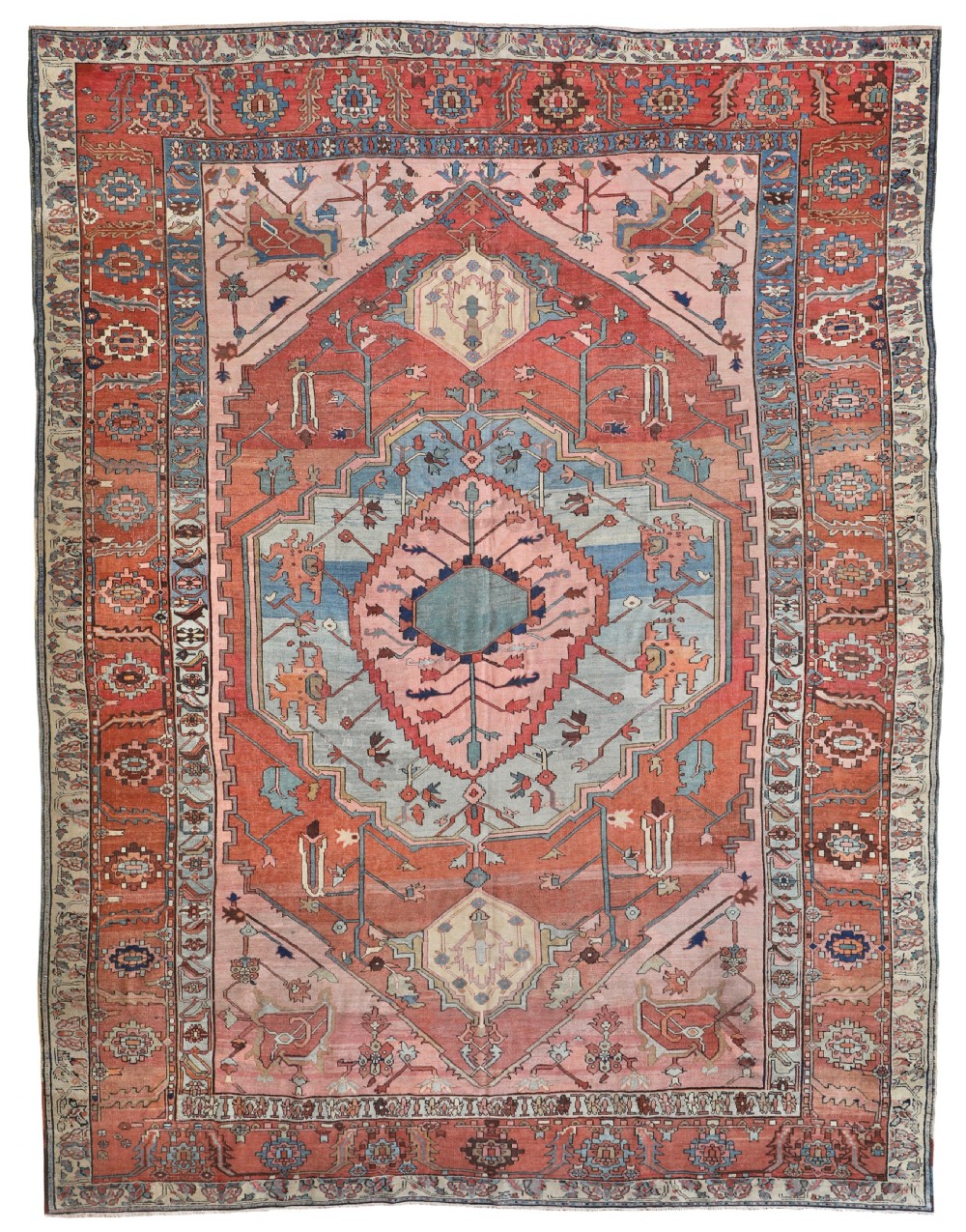 An antique Persian Bakshaish wool carpet featuring a large stepped geometric central medallion in terracotta red, light blue, and pink surrounded by stylised floral motifs and a wide decorative border.