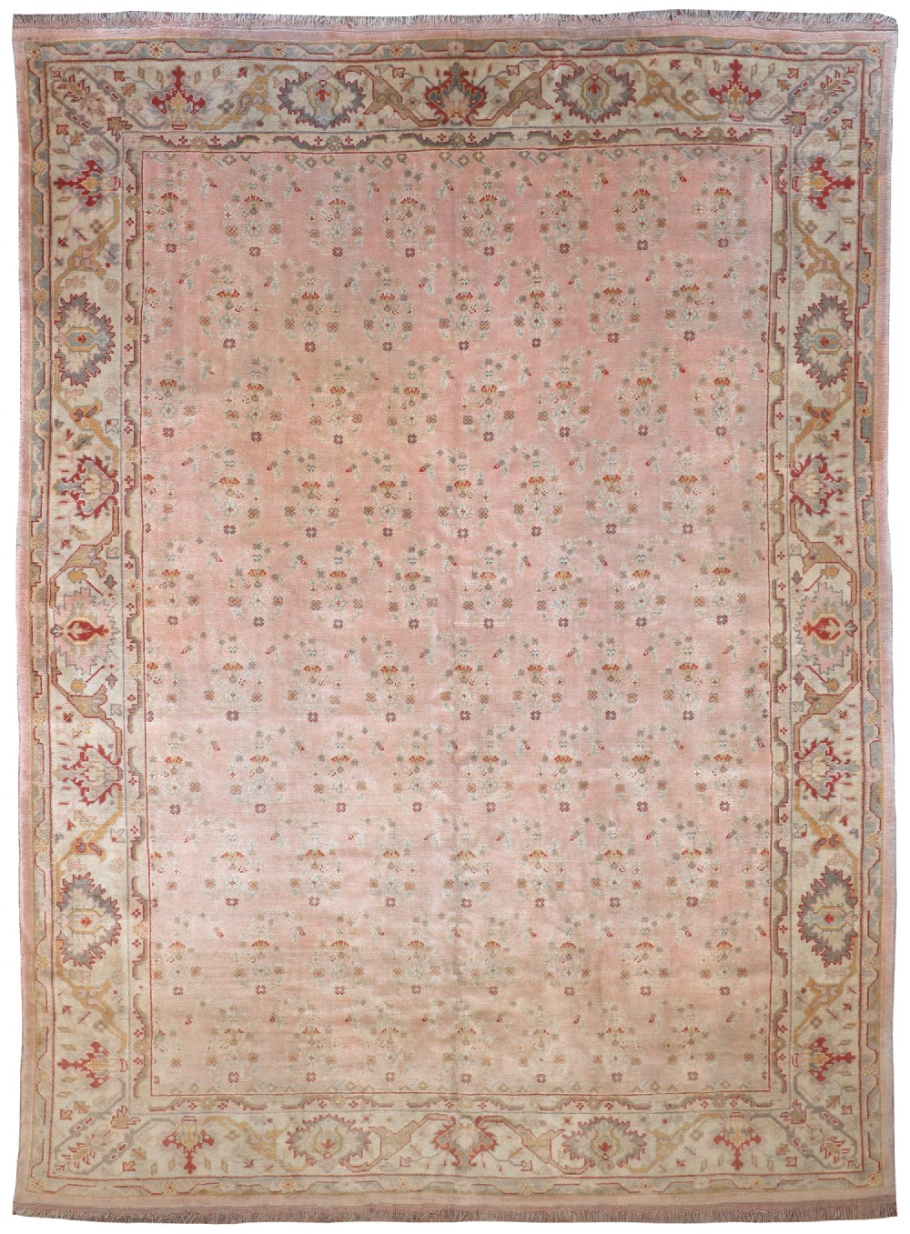 A large hand-knotted wool Ushak carpet featuring a soft rose pink field with repeating small floral motifs enclosed by a broad pastel border.