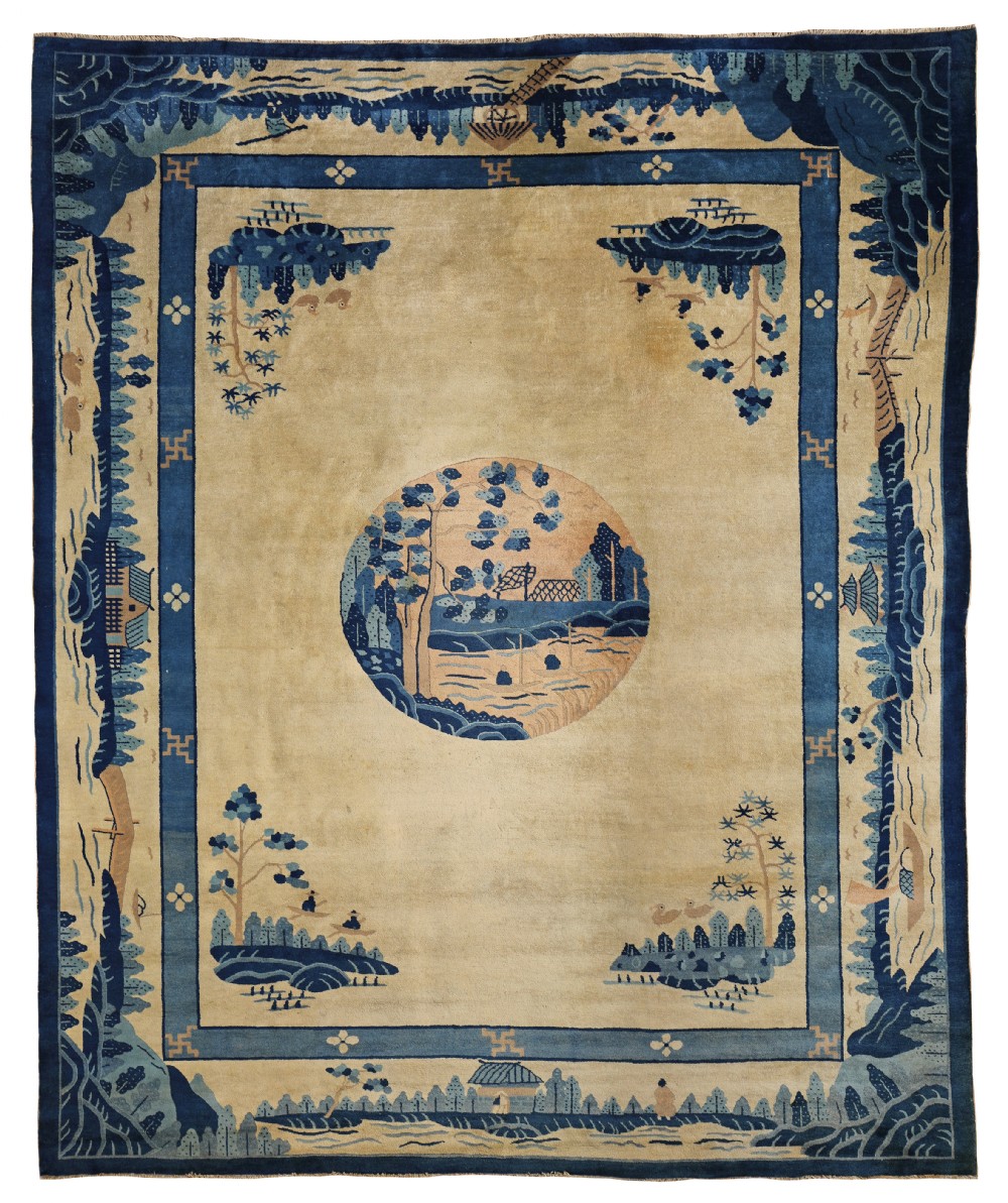 An antique Chinese rectangular wool rug featuring an indigo blue landscape border around a beige background with a circular central medallion.