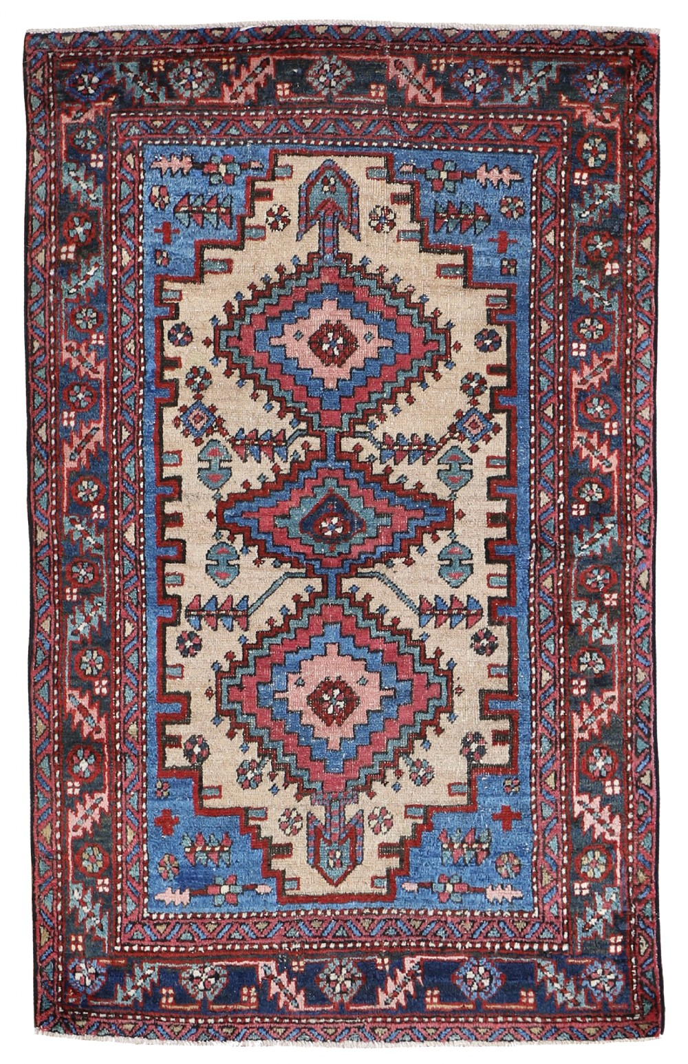 An antique hand-knotted Persian Heriz wool rug featuring three geometric stepped diamond medallions in red, blue, and cream surrounded by a detailed tribal border.