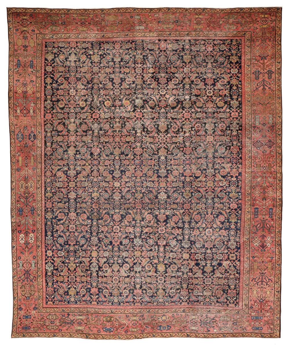 An antique Farahan wool carpet featuring a dense dark navy central field with intricate floral motifs surrounded by a wide terracotta patterned border.