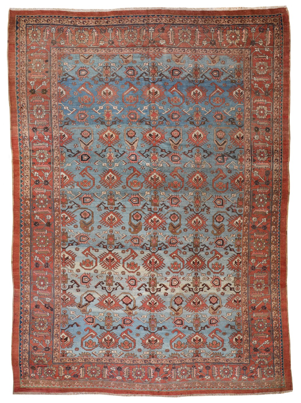 An antique hand-knotted Bakshaish Persian carpet featuring a light blue central field filled with repeating geometric motifs surrounded by a wide terracotta multi-stripe border.